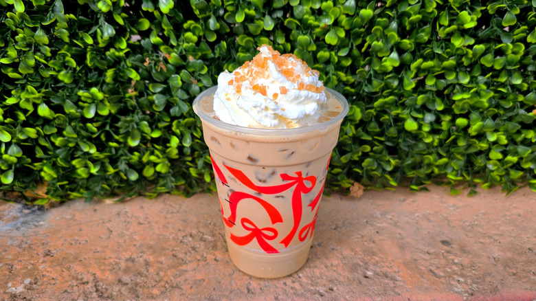 Starbucks Iced Caramel Brulée Latte in front of shrub