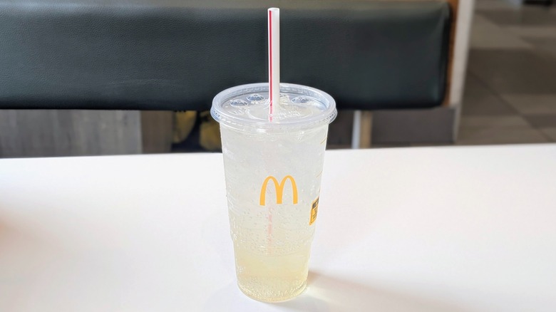 A Sprite with vanilla syrup in it in a plastic cup on a table at McDonald's