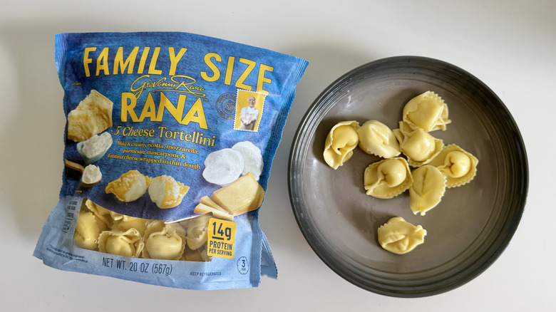 Cheese Tortellini pieces on a gray plate and package on a white table
