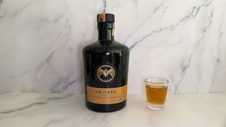 Bottle of Bacardí Gran Reserva Limitada next to shot glass on marble surface
