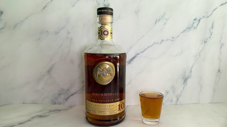 Bottle of Bacardí Gran Reserva Diez next to shot glass on marble surface