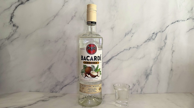 Bottle of Bacardí Coconut next to shot glass on marble surface