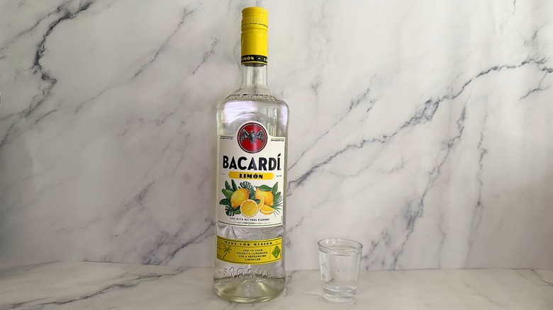 Bottle of Bacardí Limón next to shot glass on marble surface