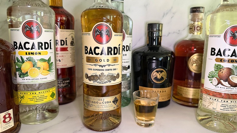 Several bottles of Bacardí around shot glass of rum on marble surface
