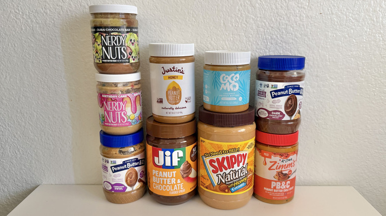 Various flavored peanut butters stacked and line on a table against a white background