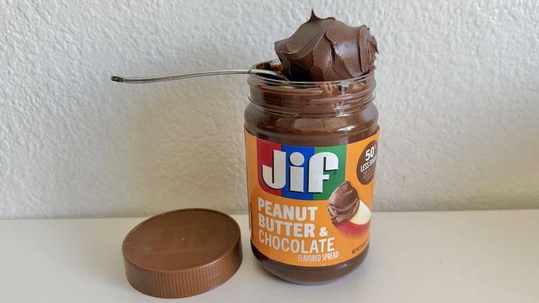 Jif Peanut Butter Chocolate Flavored Spread on a table with a spoon holding the spread on top