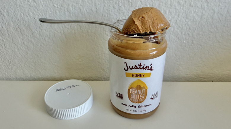 Justin's Honey Peanut Butter on a table with a spoonful on top of the jar
