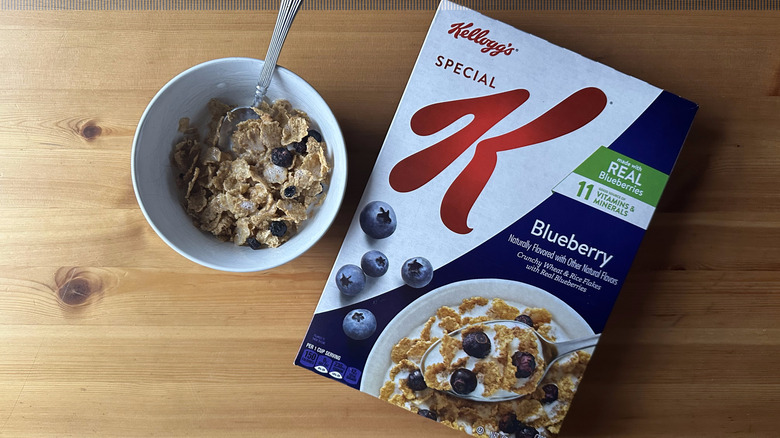 Special K Blueberry in white bowl on a wood table next to the cereal box.