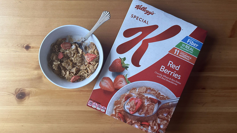 Special K Red Berries in white bowl on a wooden table next to the cereal box.