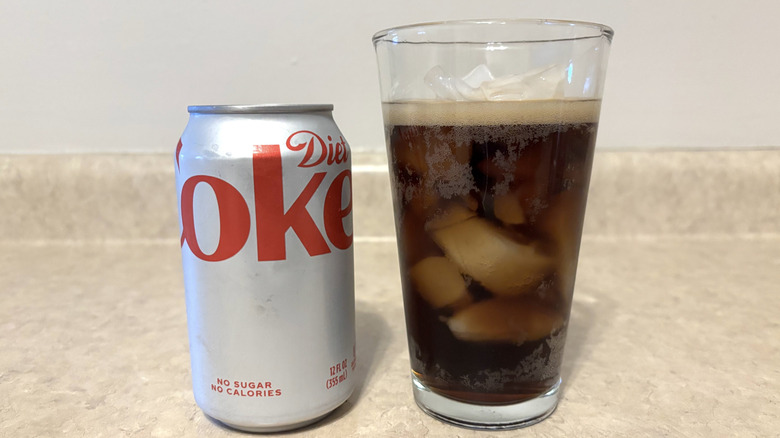 Diet Coke in can and in glass on a neutral countertop