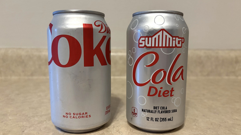 Diet Coke and Aldi Summit diet cola in cans on a neutral countertop