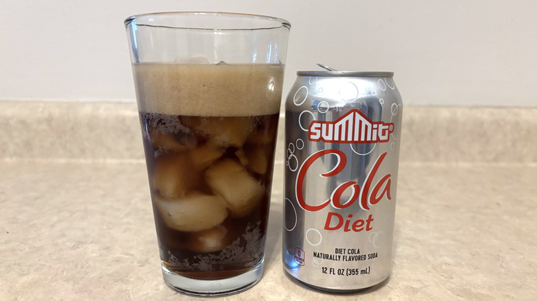 Aldi's Summit diet cola in can and glass on neutral countertop