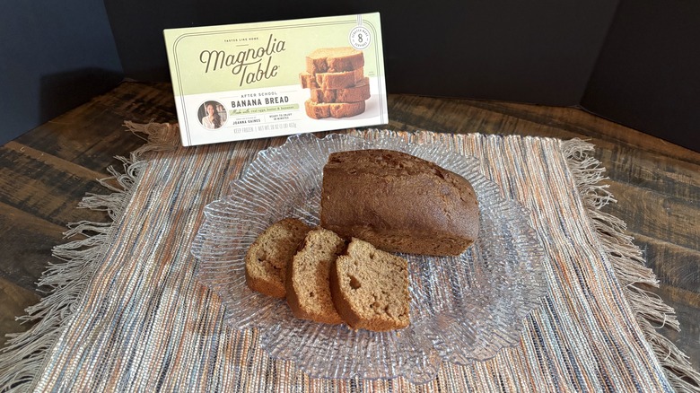 Magnolia Table banana bread on platter and placemat on wooden table and black background.
