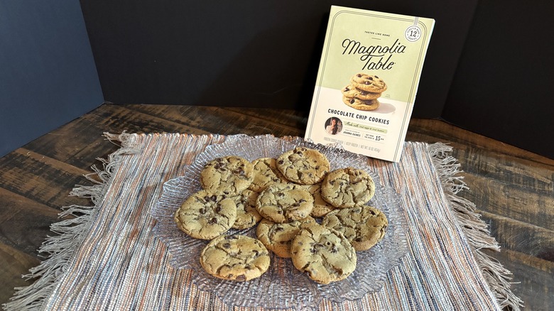 Magnolia Table chocolate chip cookies on platter and placemat on wooden table and black background.