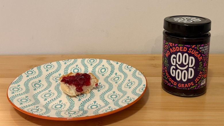 jar of Good Good grape jelly with a piece of bread and jelly on top