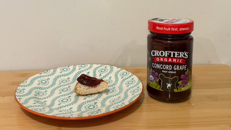 Jar of Crofter's Fruit Spread with a piece of bread and the jelly on top next to it