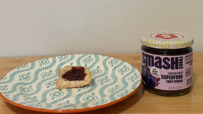 Jar of Smash Fruit Spread with a piece of bread and the jelly on top next to it
