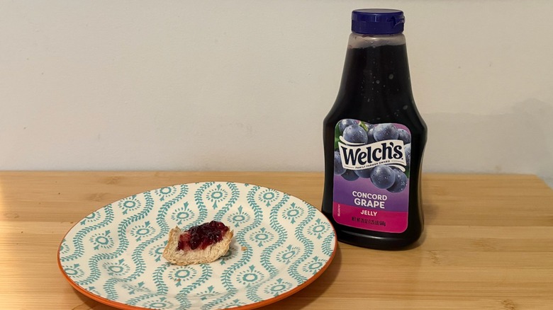 Welch's Grape Jelly with a piece of bread and the jelly on top next to it
