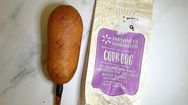 Walmart corn dog next to wrapper on marble surface