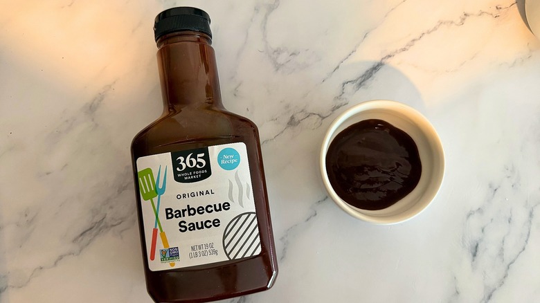 Bottle of 365 Original BBQ Sauce on table next to small white bowl of sauce