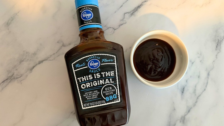 Bottle of Kroger Original BBQ Sauce on table next to small white bowl of sauce
