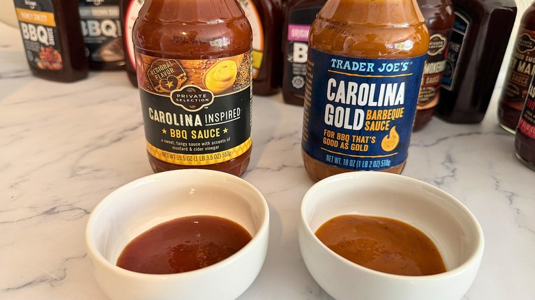 Two bottles of Carolina-inspired BBQ sauce behind two small white dishes of sauce