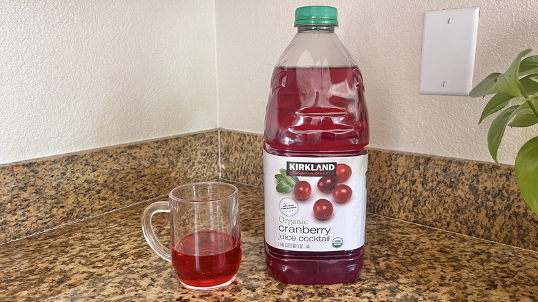 Cranberry juice cocktail container with glass next to it