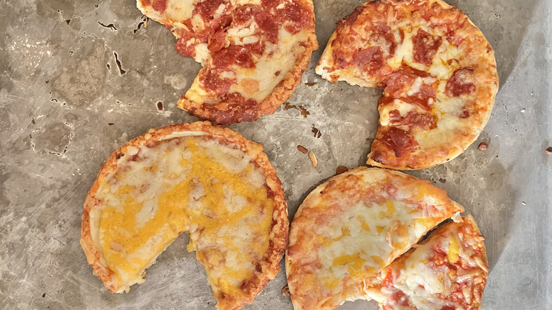 Four partially eaten pizzas on a baking tray