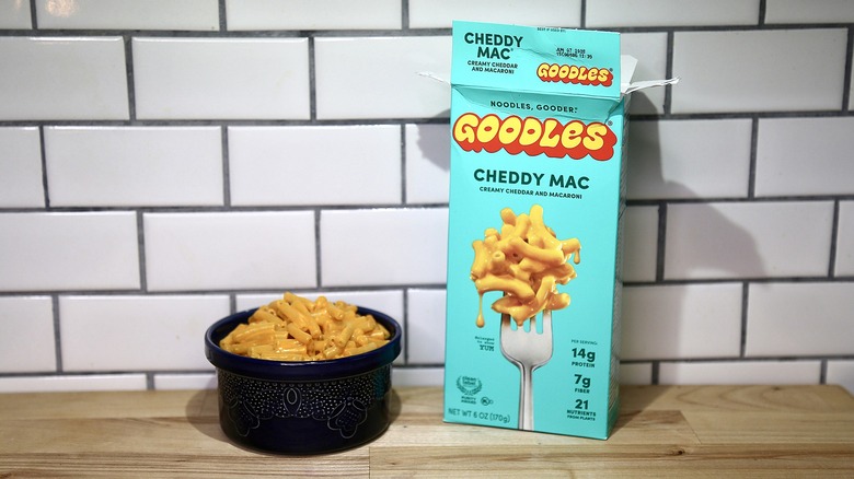 Goodles box of max and cheese next to and bowl of cooked mac and cheese