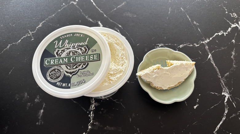 Trader Joe's whipped cream cheese container next to bagel piece on plate