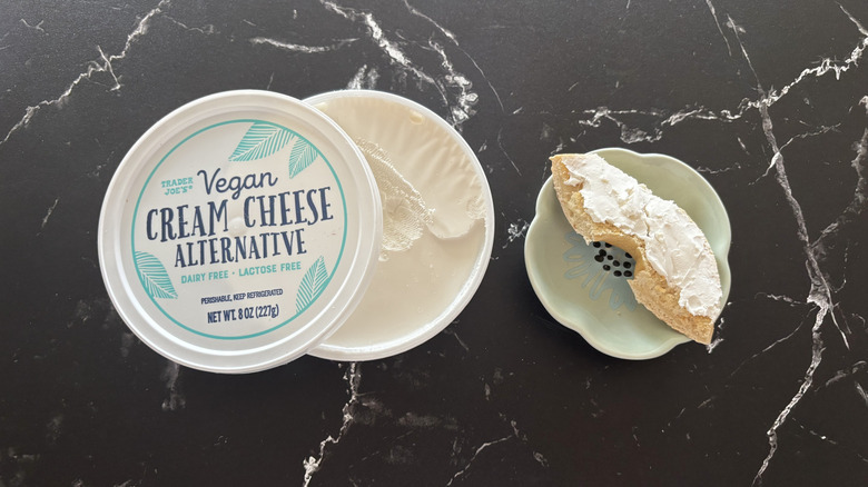 Trader Joe's vegan cream cheese container next to bagel piece on plate