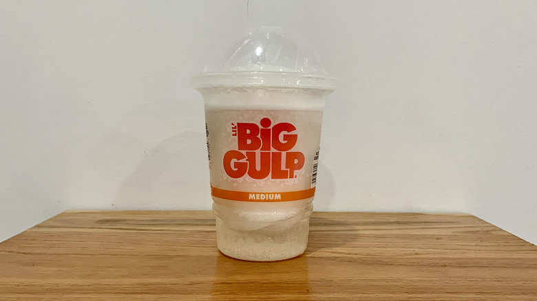 Confetti Chill Slurpee in plastic cup on wooden shelf with white background
