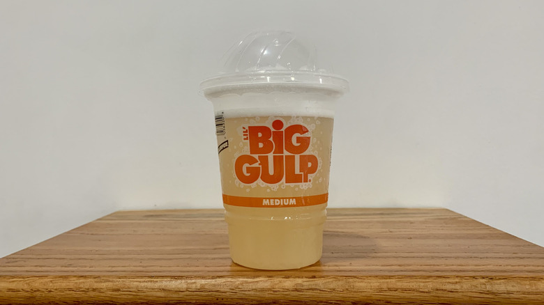 Fresca Slurpee in plastic cup on wooden shelf with white background
