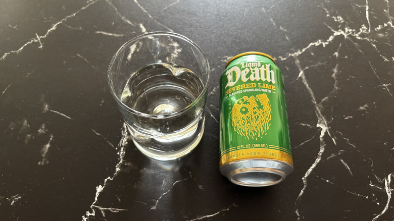 Glass of sparkling water next to Liquid Death Severed Lime soda can