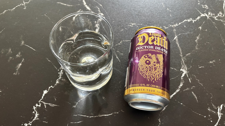 Glass of sparkling water next to Liquid Death Doctor Death soda can