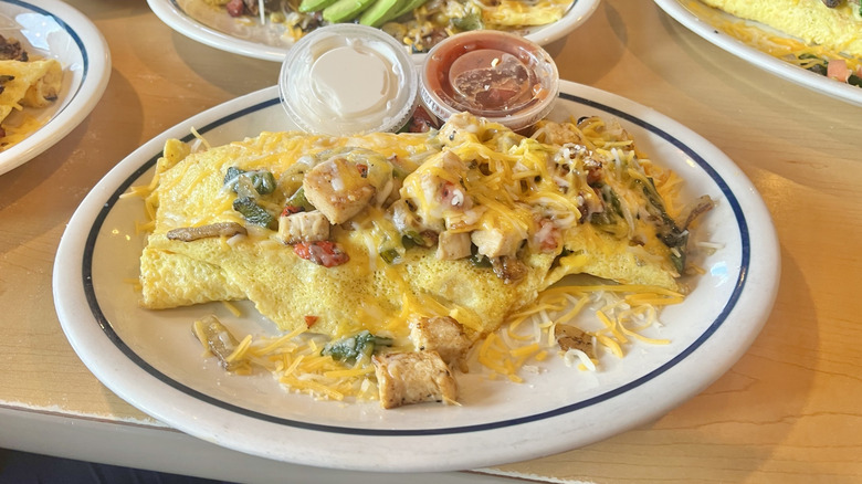 Chicken Fajita Omelette served on an oval-shaped plate with two salsas on the side