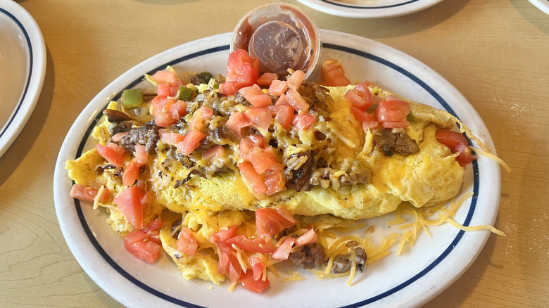 IHOP Big Steak Omelette on white plate with salsa served on the side in a plastic container