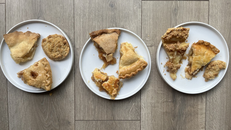 Assorted apple pie slices on three white plates
