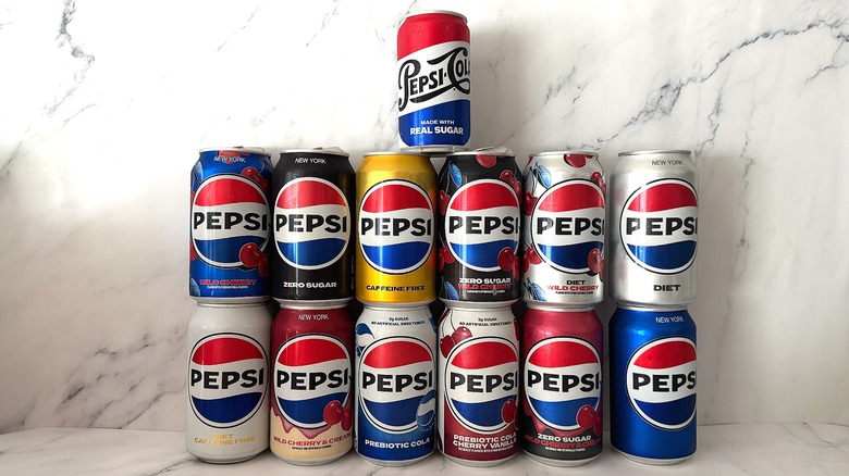 Thirteen cans of Pepsi stacked two high on marble background