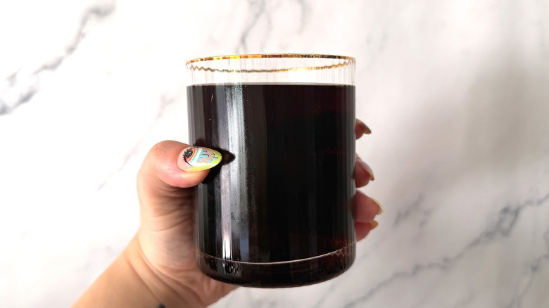 Hand holding glass of Pepsi against marble background