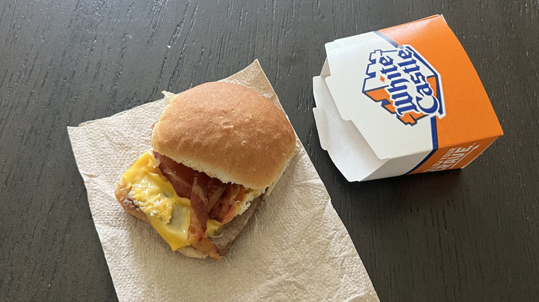 White Castle bacon cheese slider with the top bun on the side and a box next to it