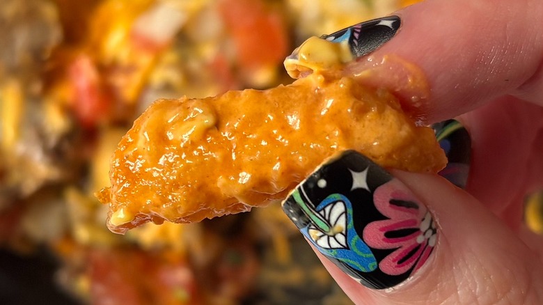 Close-up of fingers holding Taco Bell fry loaded with volcano sauce