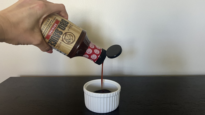 Pouring out Buc-ee's BBQ sauce into white ramekin.