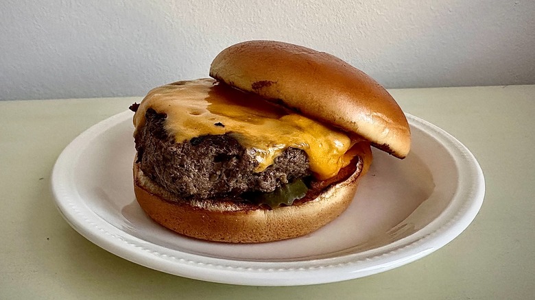 Longhorn Steakhouse's cheeseburger on a small white plate in front of a neutral background