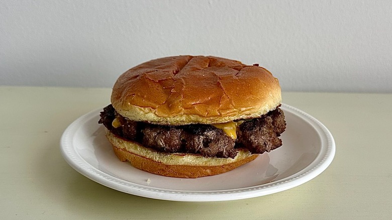 Chili's cheeseburger on a small white plate in front of a neutral background