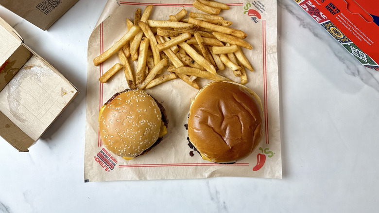 McDonald's Quarter Pounder with Cheese aside the Chili's Big QP burger on brown parchment paper with fries on the side