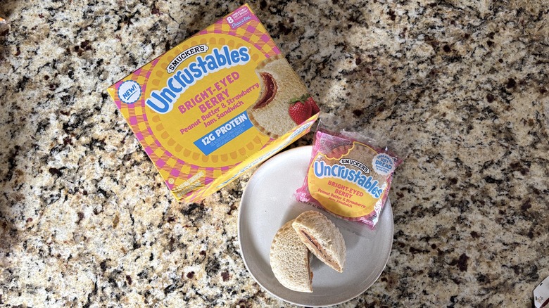 Bright-eyed berry Uncrustables in box, package, and on plate on marble countertop