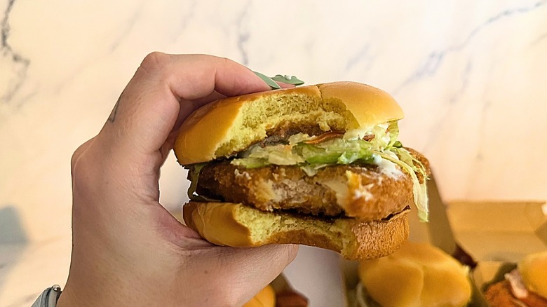 Hand holding Wendy's chicken sandwich against marble background