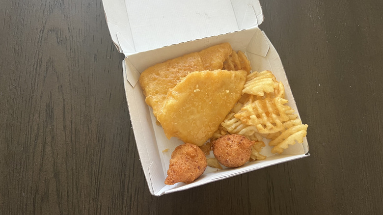 Long John Silver's 2 piece fish meal in to-go box on a wooden table
