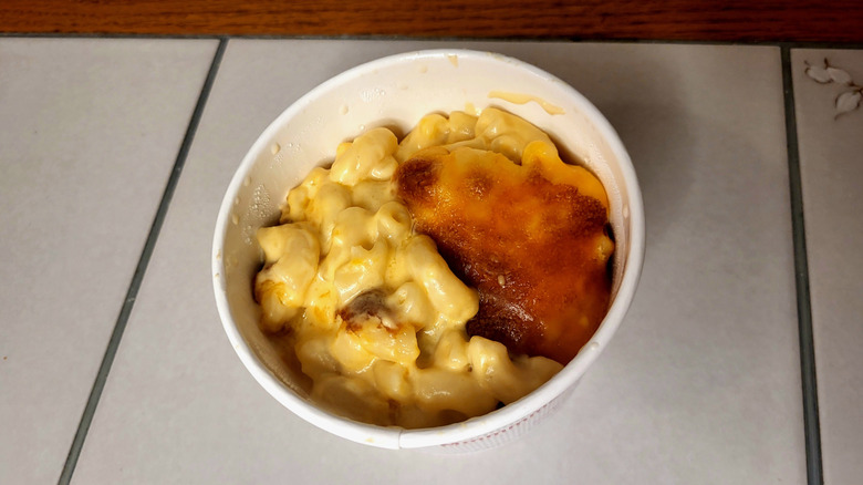 A takeout container filled with baked macaroni and cheese.